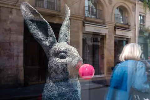 Kunstobject, konijn met bel van kauwgom in mond, reflectie van voorbijganger